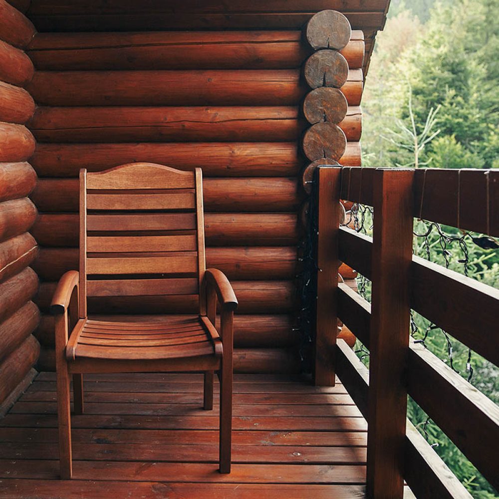 wooden-chair-on-porch-of-cabin-among-woods-2021-08-29-06-08-25-utc-copy.jpg